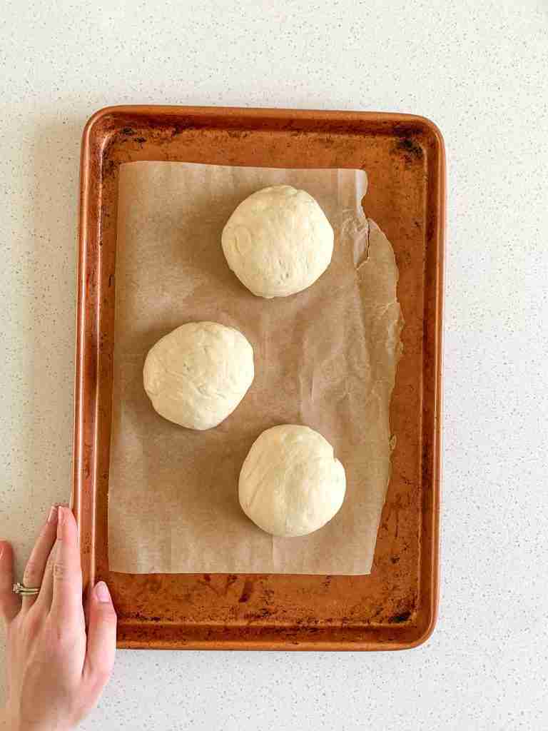 hand moving pan of bun dough to fridge