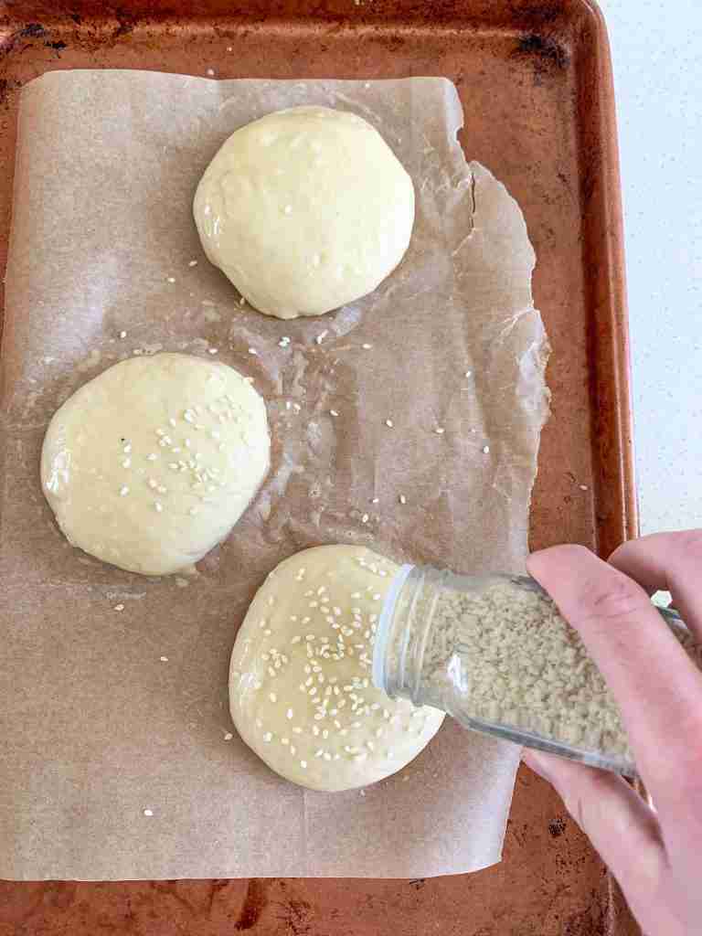 hand sprinkling sesame seeds on dough