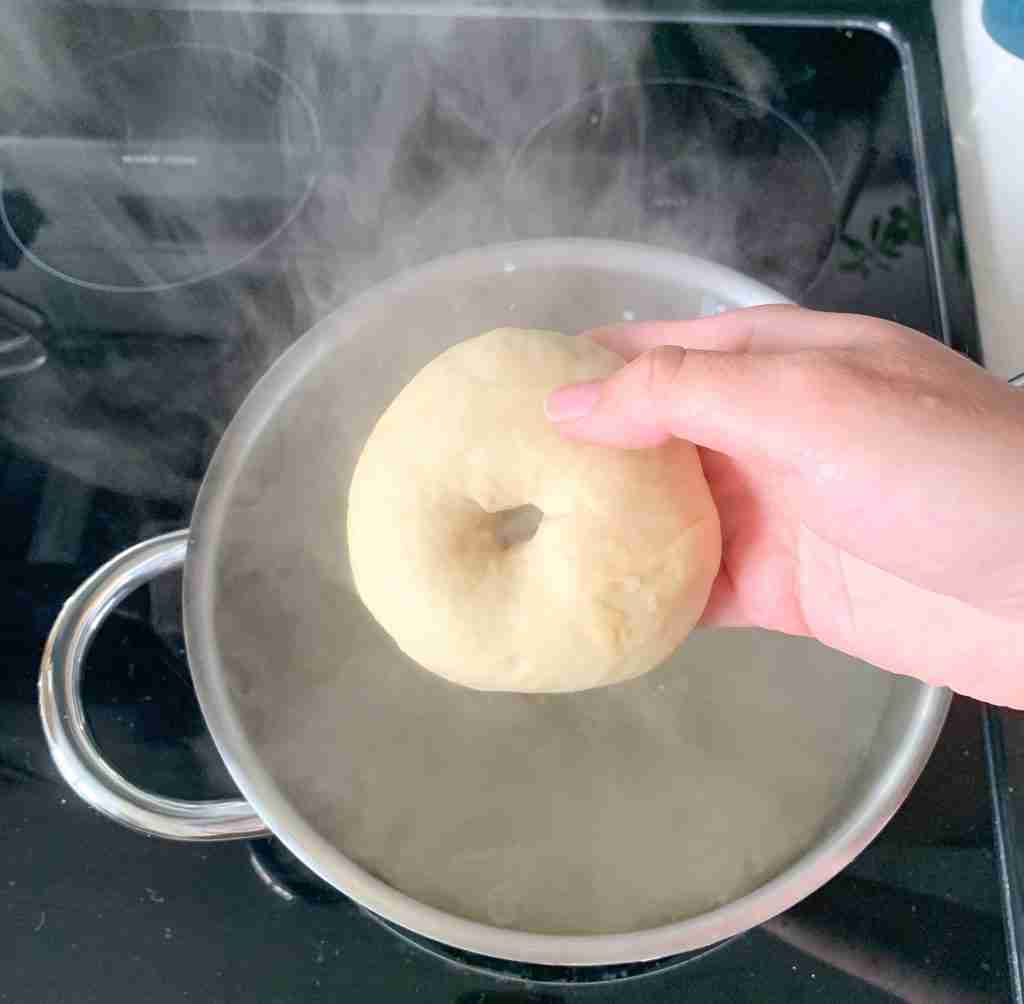 hand dropping bagel in water bath