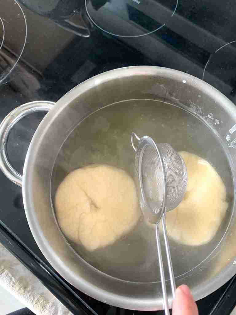 hand getting bagels out of water bath
