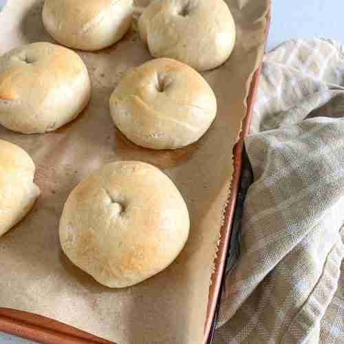 bagels on a baking tray with a towel beside it