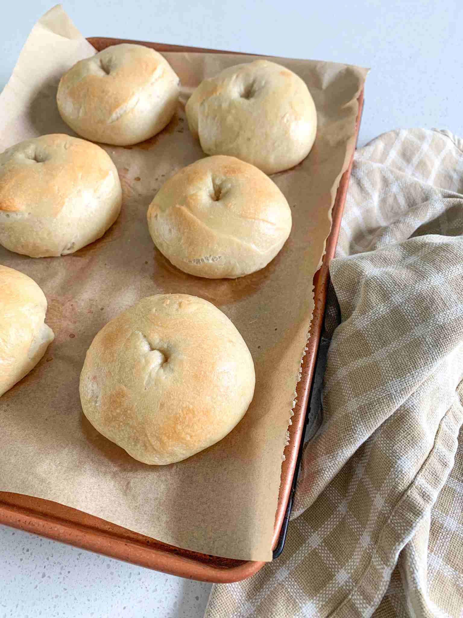 bagels on a baking tray with a towel beside it