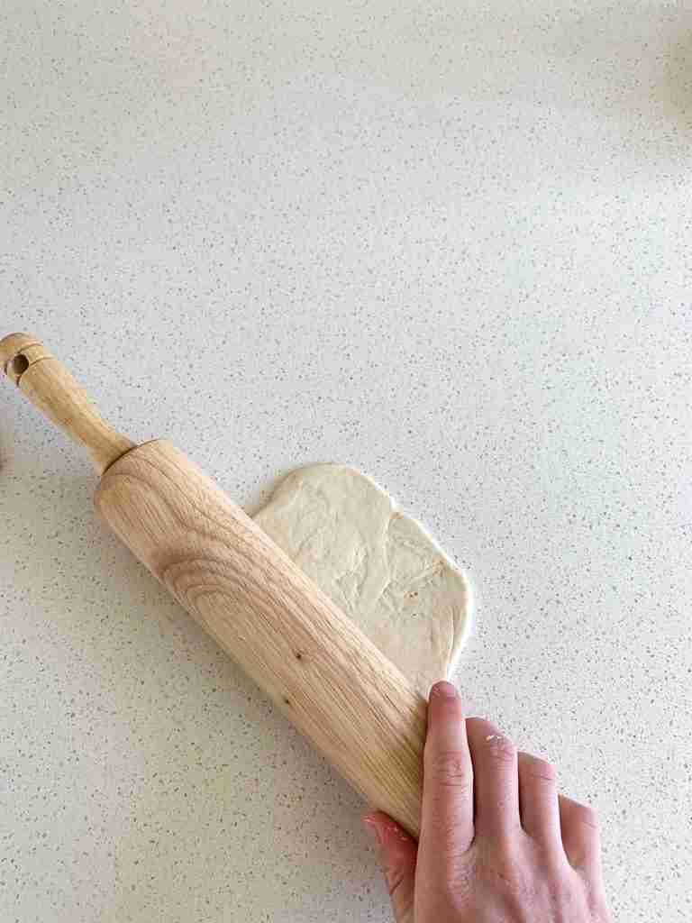 hand rolling out dough into a circle
