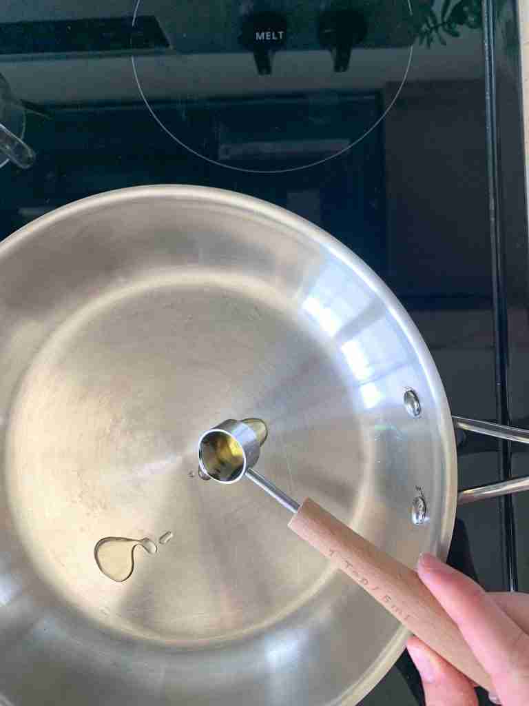 hand pouring oil in a skillet