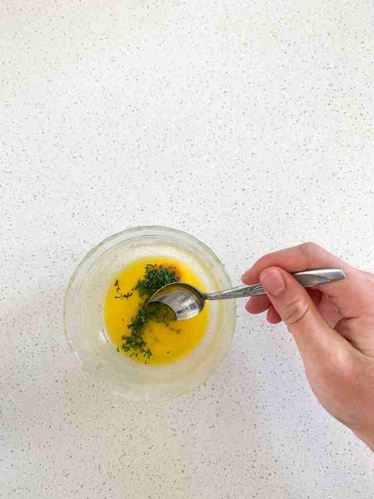 hand mixing butter and herbs in a bowl