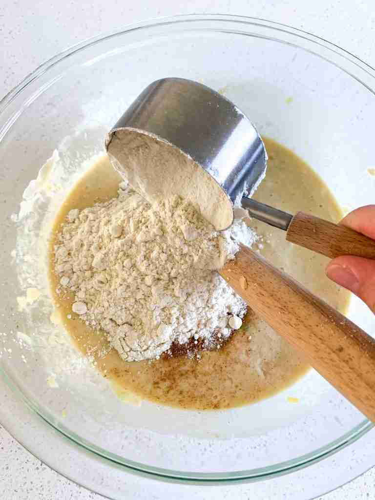 flour getting poured into a mixing bowl with ingredients