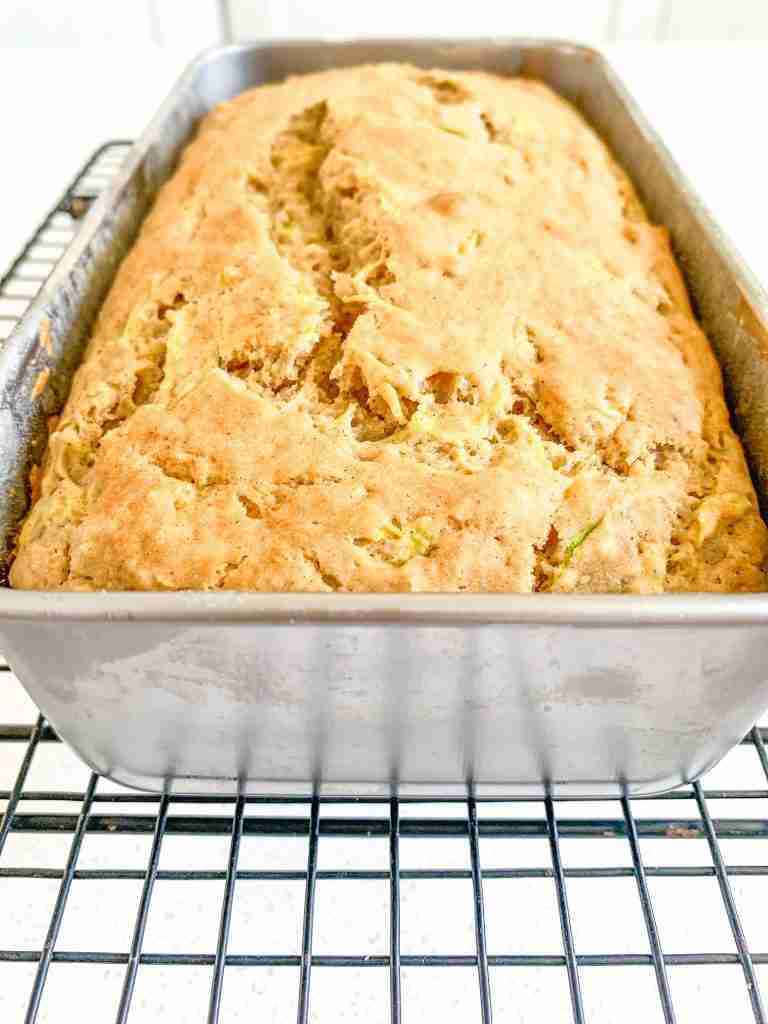 bread loaf in a bread pan cooling on a rack