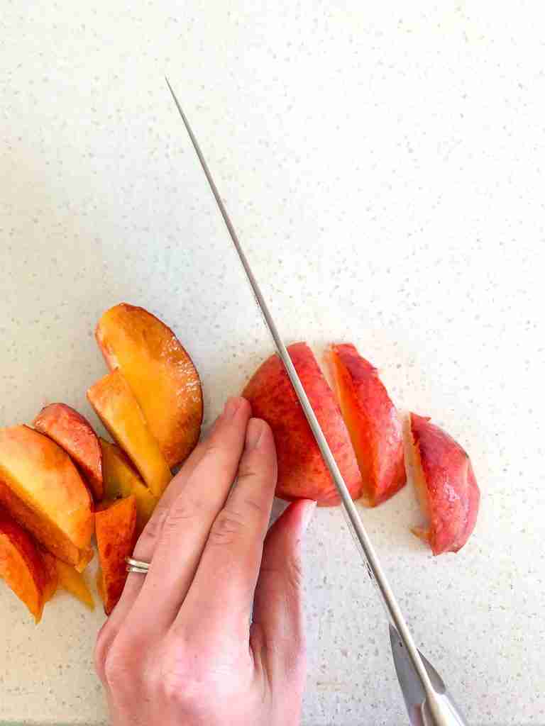 hands cutting up peaches