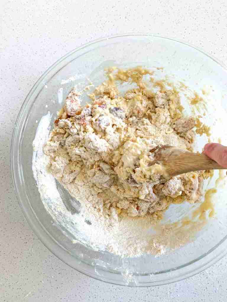 hand using a spoon to combine dough together