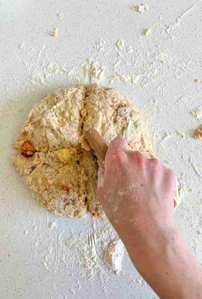 hand cutting dough circle into pieces for scones