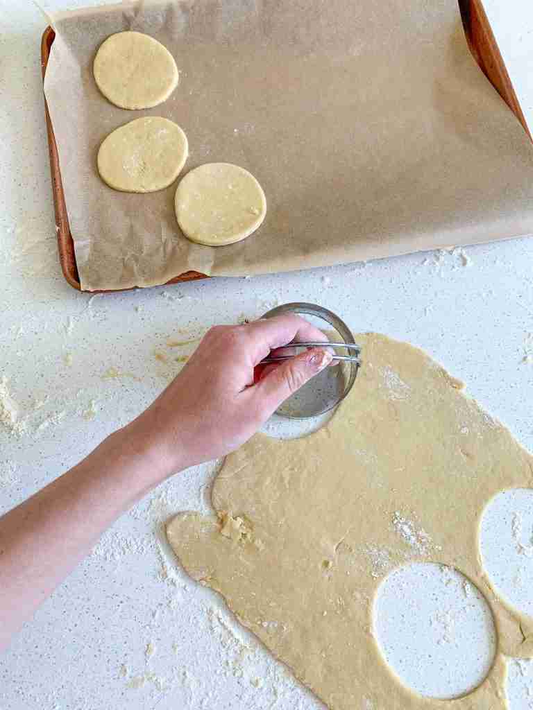 hand cutting cookies and placing them on a sheet pan 