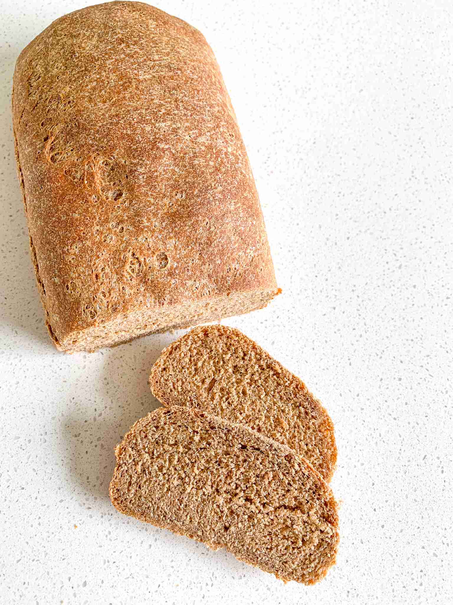 over head shot of a wheat loaf with 2 slices off