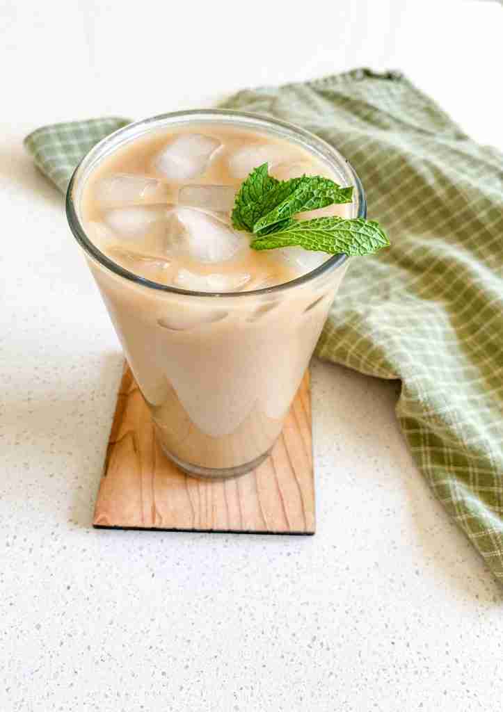 iced coffee on a wooden coaster with mint leaves garnished on top