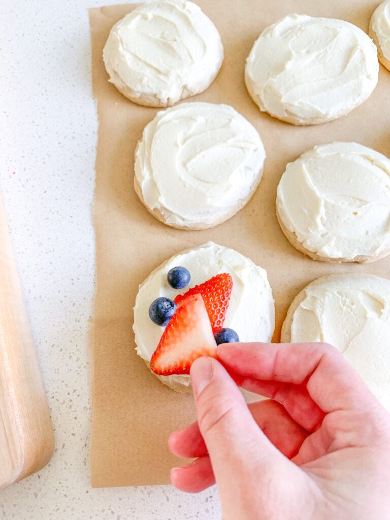 adding berries to frosted sourdough sugar cookies