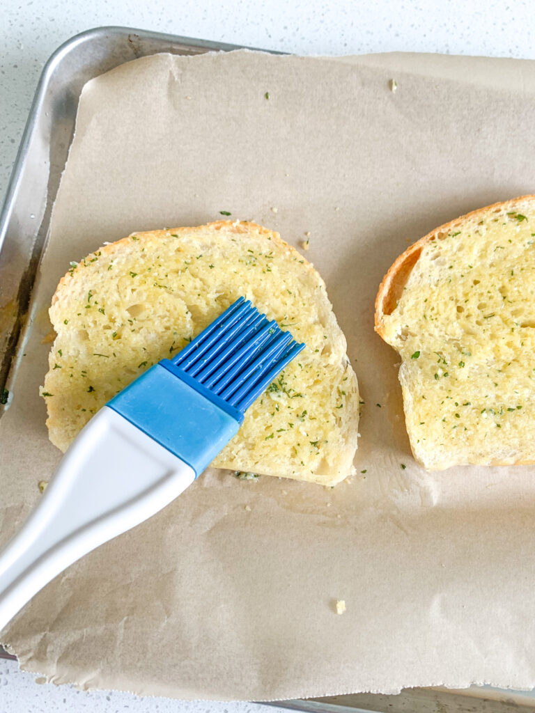 brushing sourdough bread with garlic butter