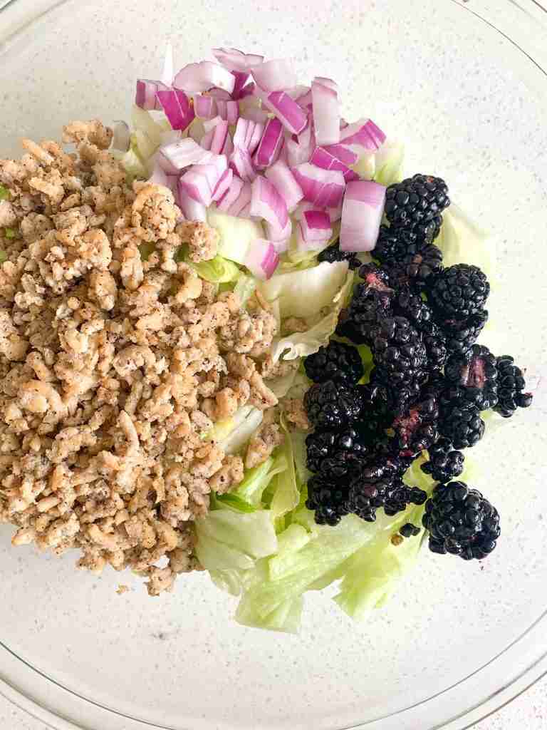 up close shot of bowl full of chicken berries lettuce onion