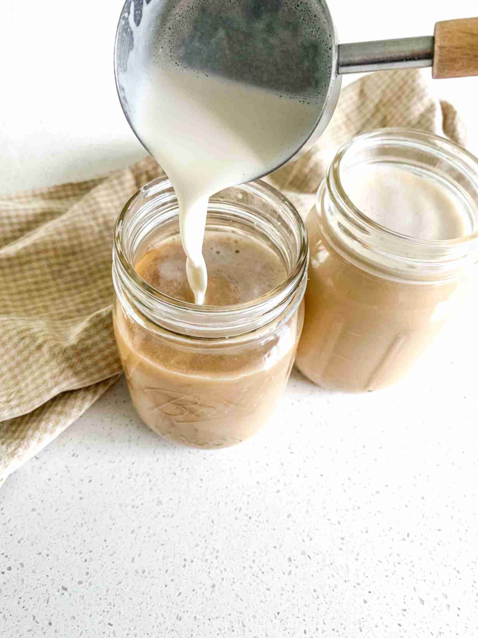 milk being poured into a glass of tea