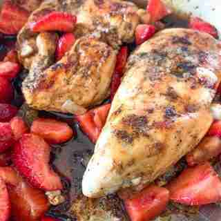 chicken breast with sauce and strawberries in a pan