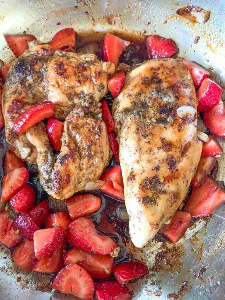 chicken breast with sauce and strawberries in a pan