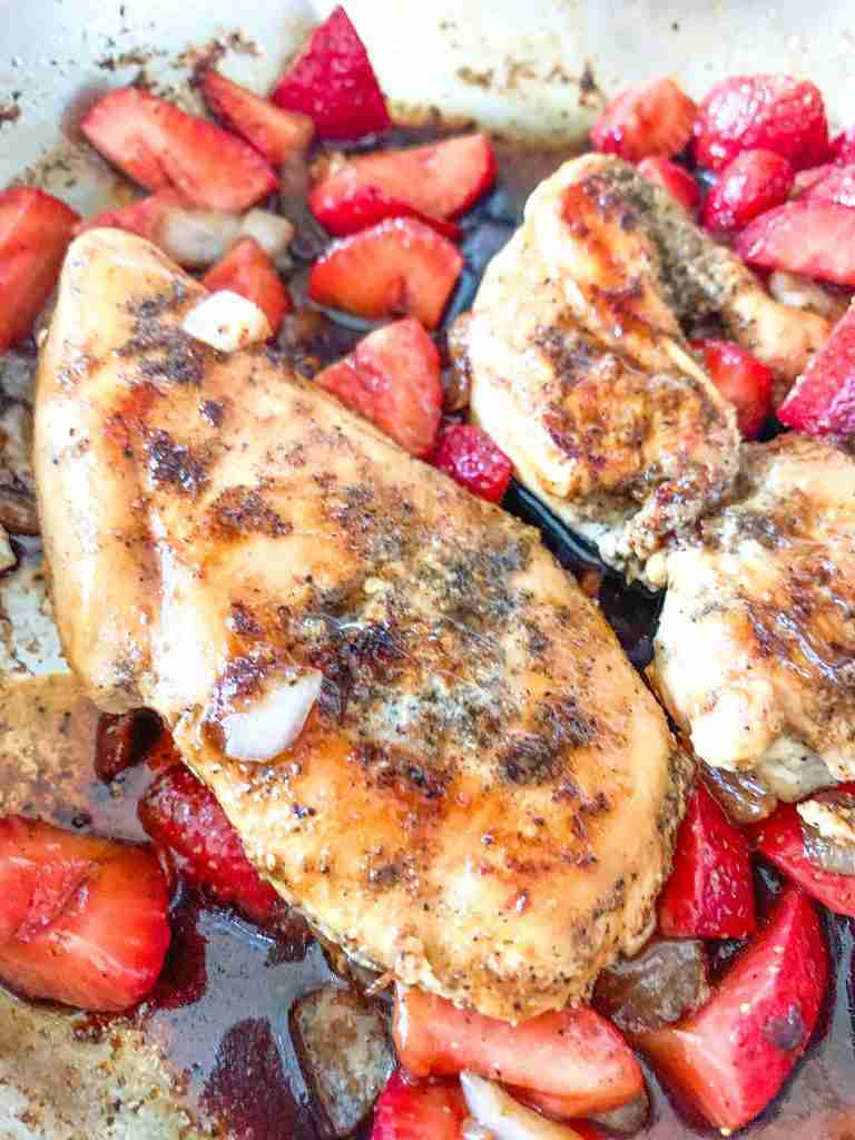 chicken breast with sauce and strawberries in a pan