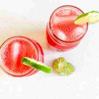 two glasses of watermelon iced drink with lime wedges