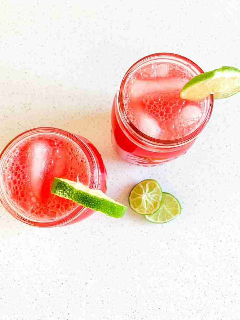 two glasses of watermelon iced drink with lime wedges