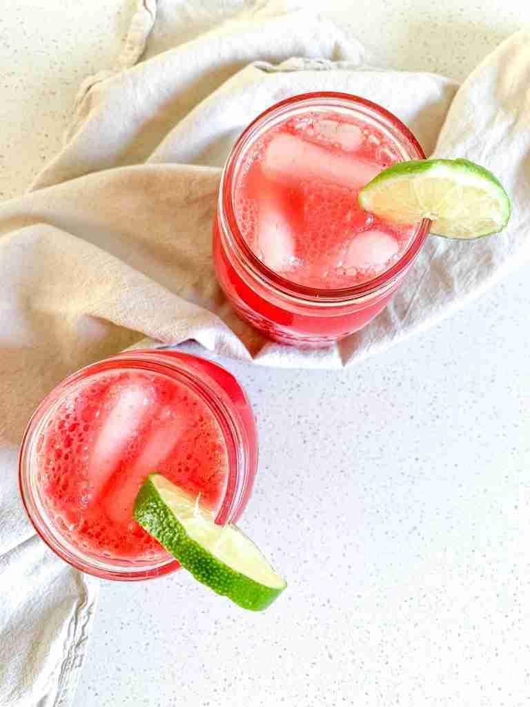 two glasses of watermelon iced drink with lime wedges