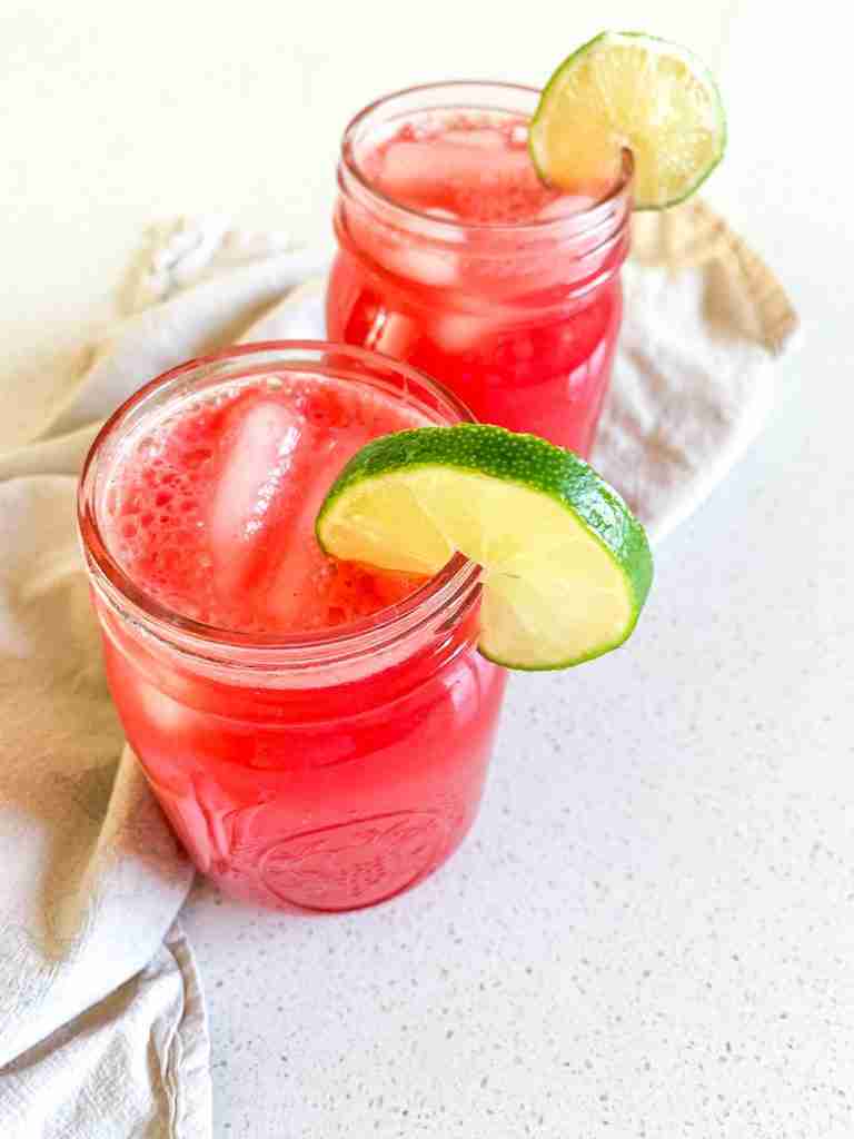 two glasses of watermelon iced drink with lime wedges