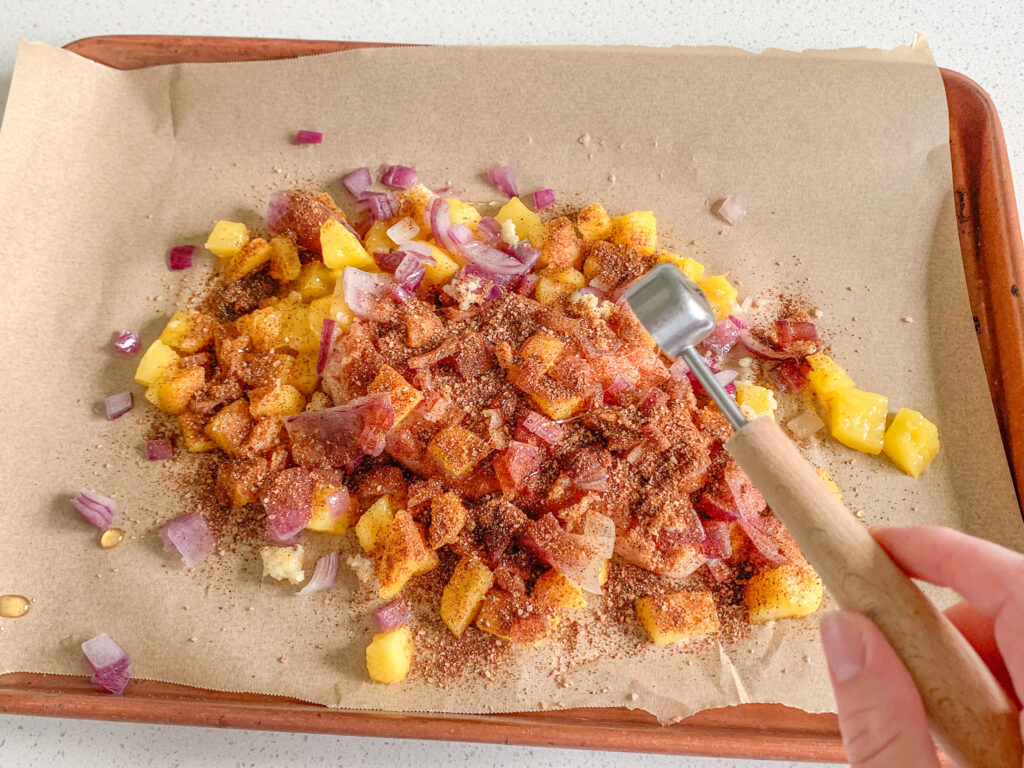 adding honey to chicken and produce on sheet pan