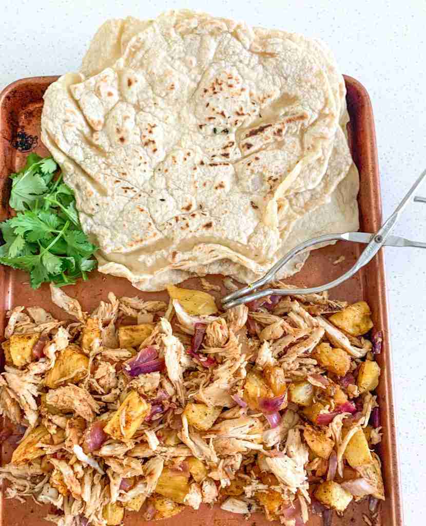 shredded taco chicken and tortillas on a sheet pan