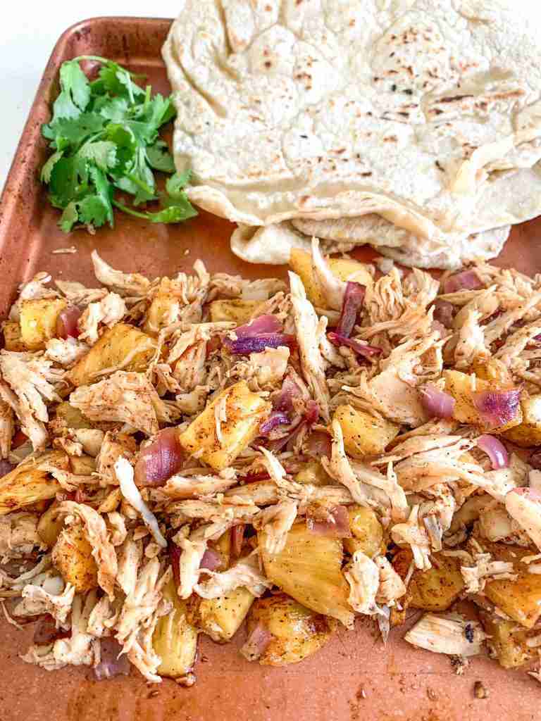 shredded taco chicken and tortillas on a sheet pan