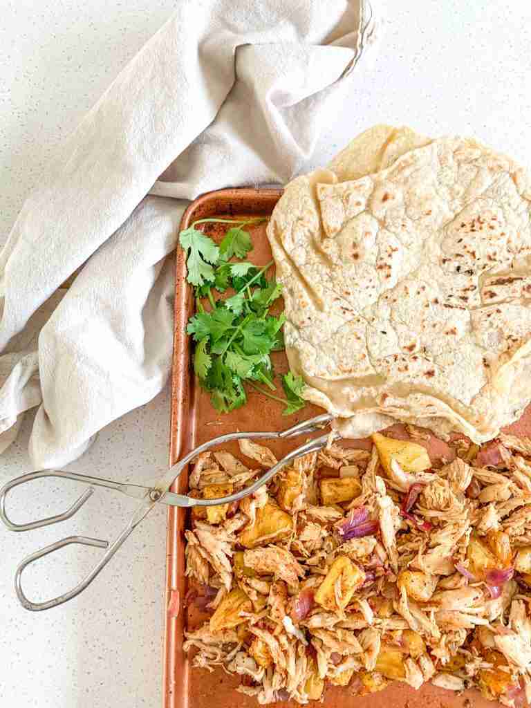 shredded taco chicken and tortillas on a sheet pan