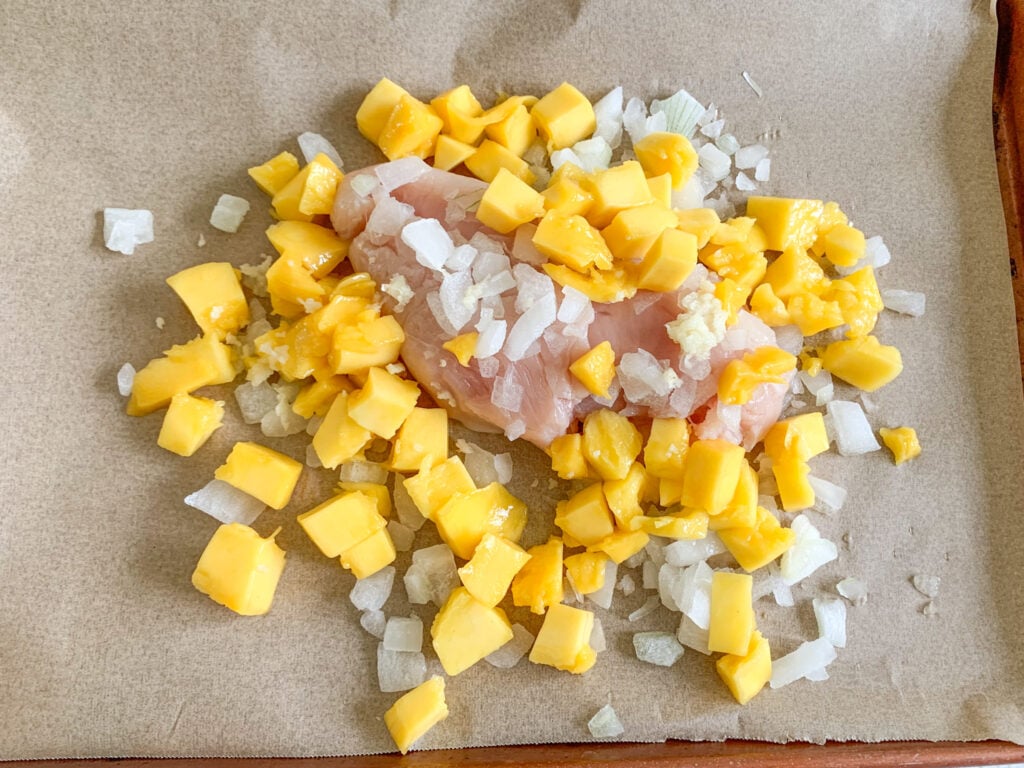 chicken, mangos, and onions on the sheet pan