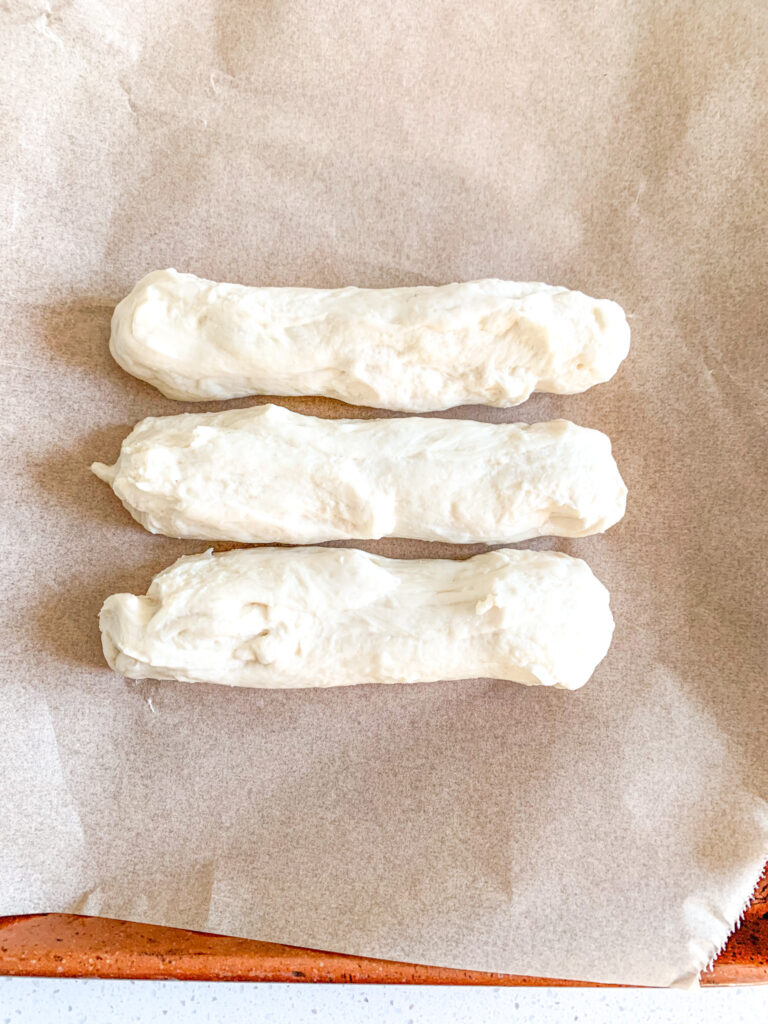 hot dog bun dough shaped and on a pan