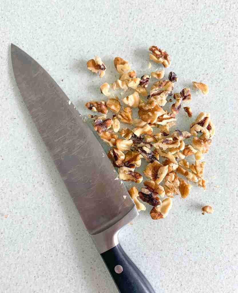 walnuts chopped laying beside a knife