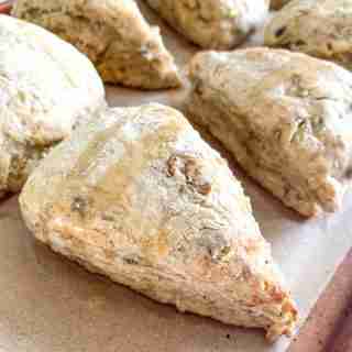 baked sourdough banana walnut sourdough scones sitting on a sheet pan drizzled with maple syrup
