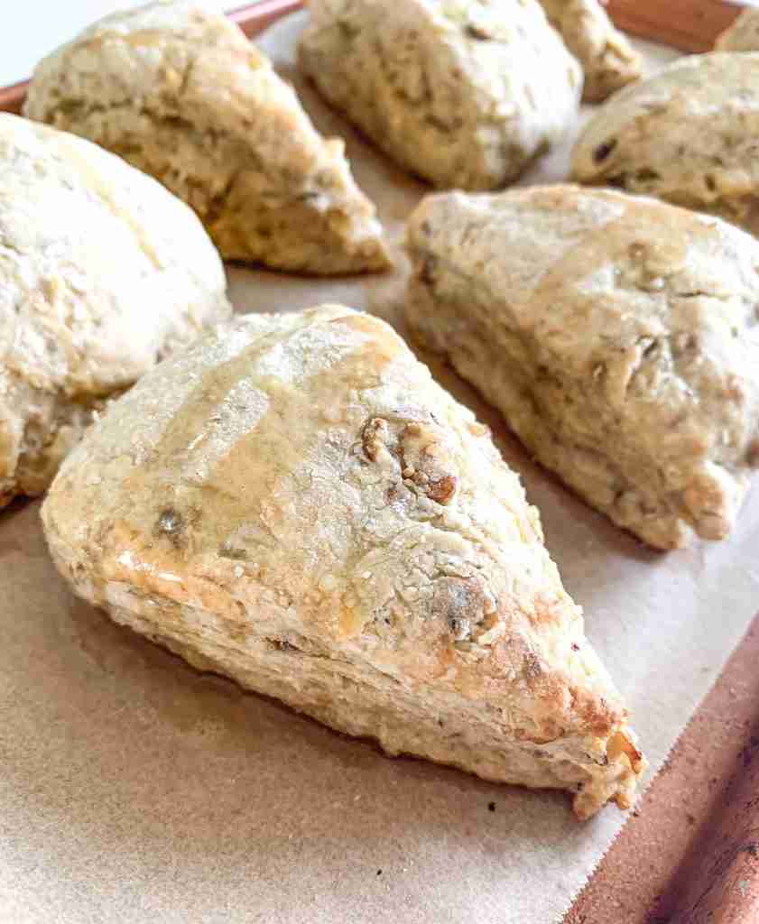 baked sourdough scones sitting on a sheet pan drizzled with maple syrup