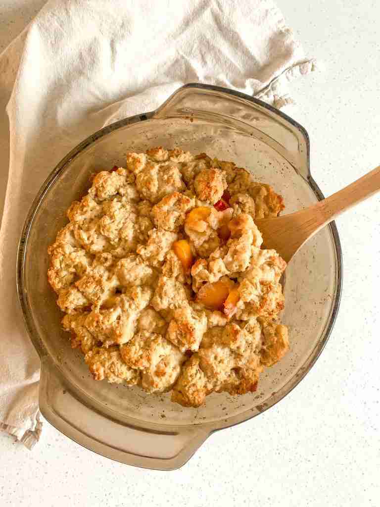 sourdough peach cobbler being served with a spoon