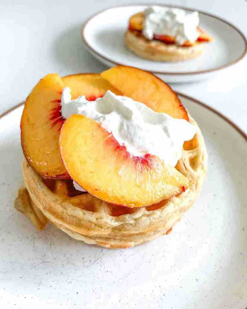 stack of peach waffles with whipped cream
