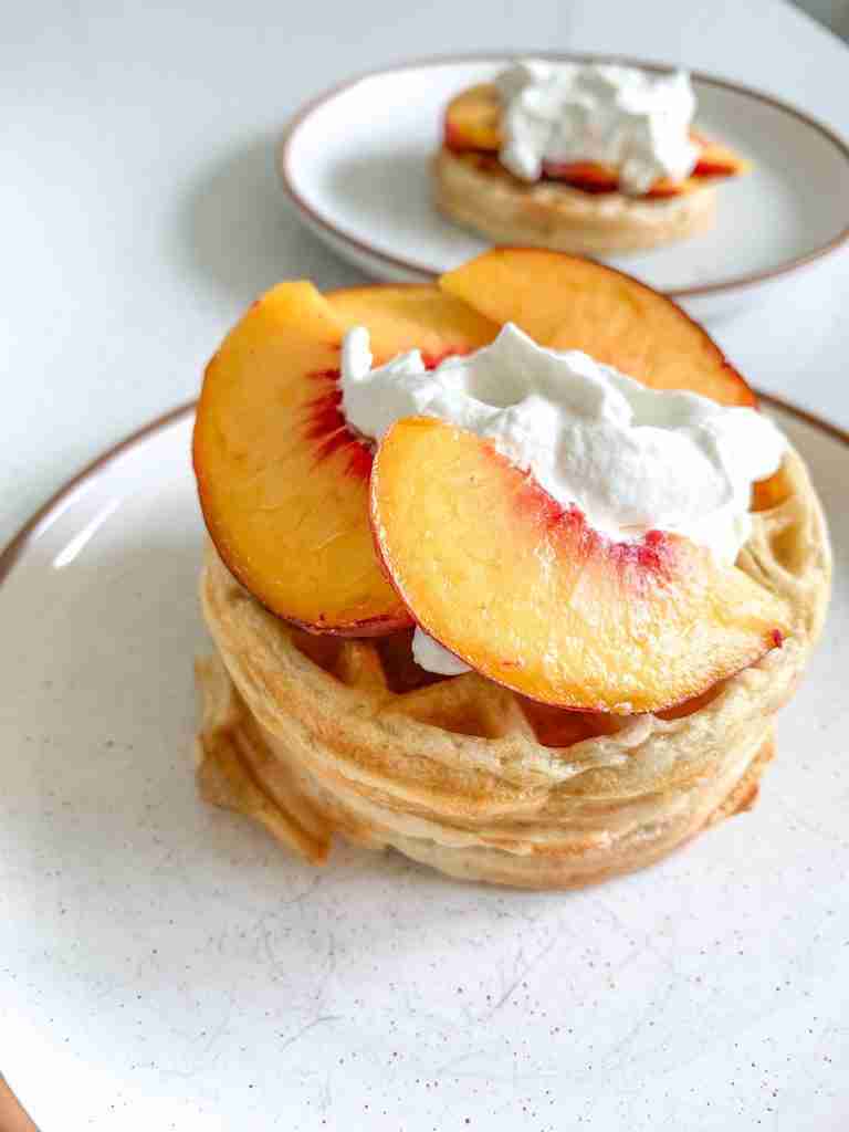 stack of peach waffles with whipped cream