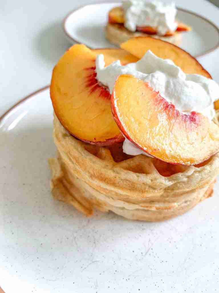 stack of peach waffles with whipped cream