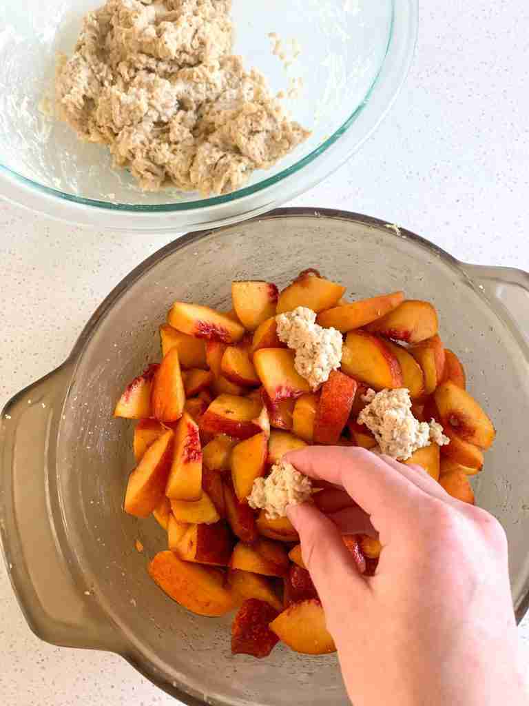 hand dropping biscuit dough on peaches