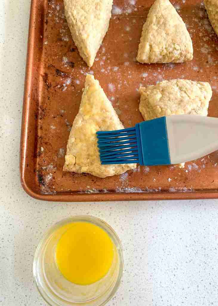 brushing butter on top of scones before baking