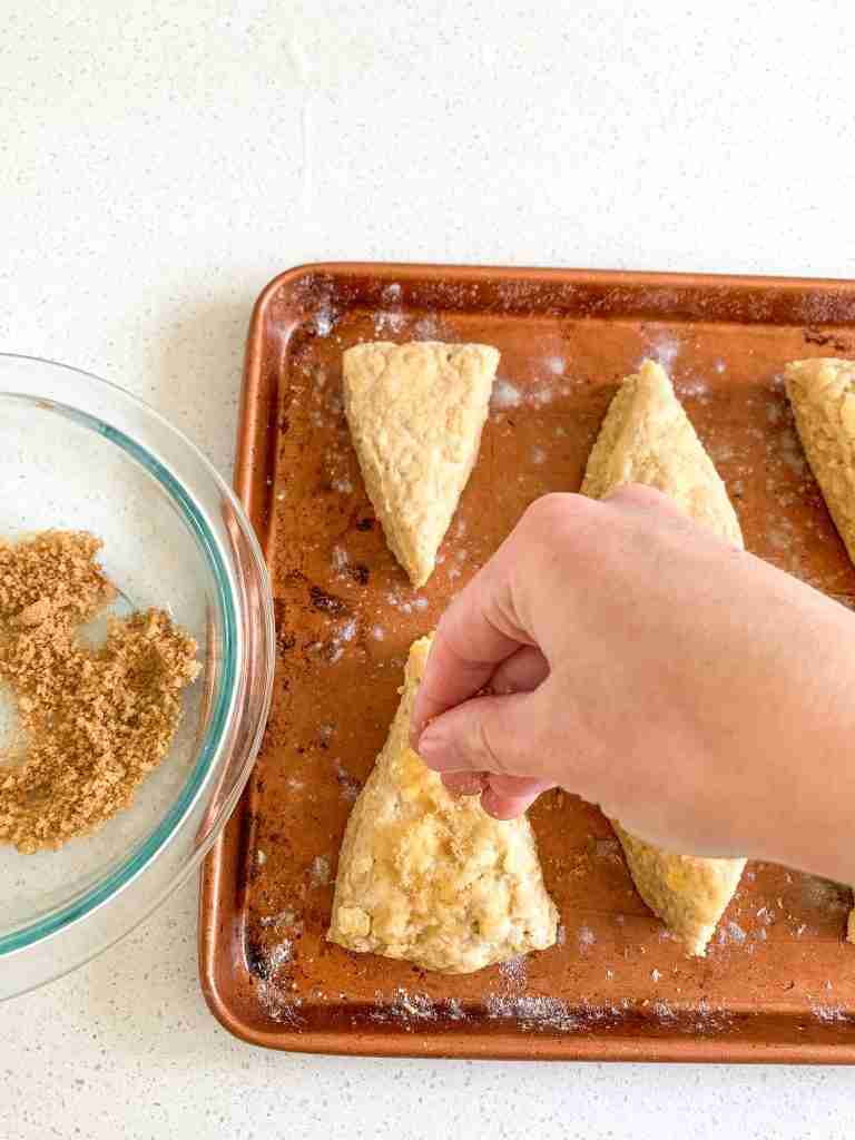 hand sprinkling cinnamon brown sugar over scones