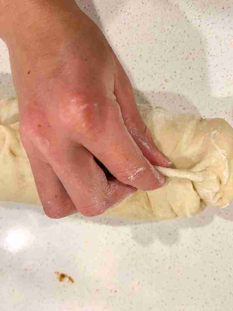 hand pinching bread dough into a log