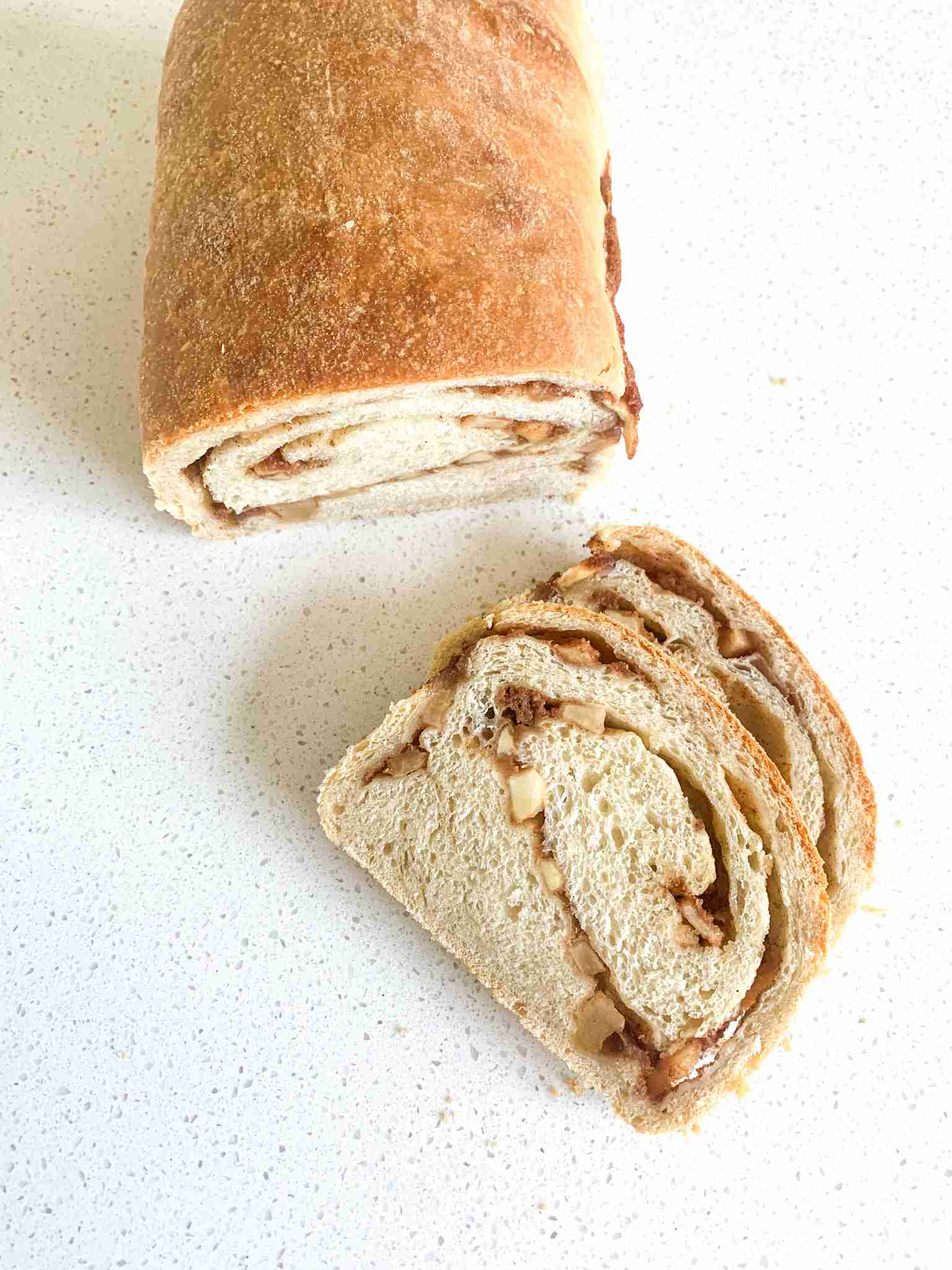 loaf of sourdough apple bread with a few slices laying beside it