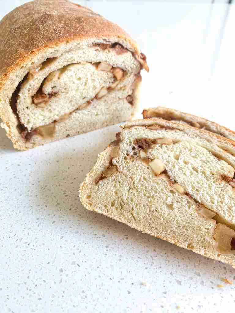 loaf of sourdough apple bread with a few slices laying beside it