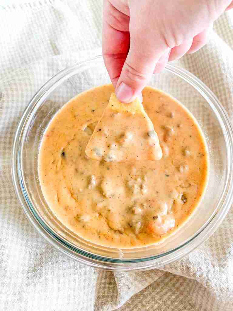 hand dipping a chip into homemade rotel dip