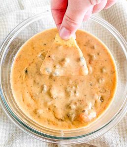 hand dipping a chip into homemade rotel dip