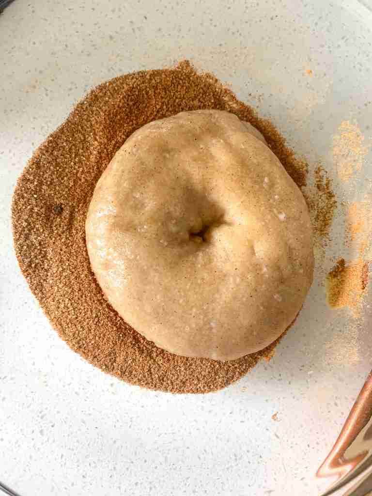 unbaked bagel getting coated in cinnamon sugar